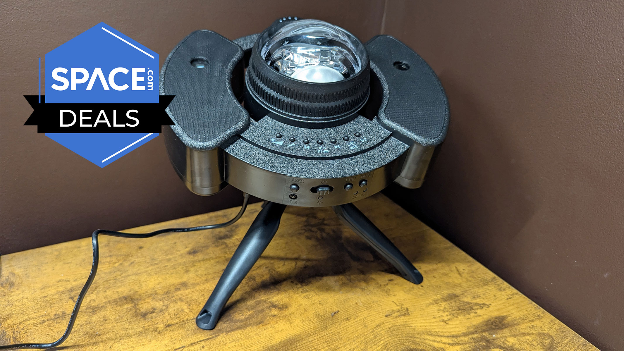 A round dark object placed on a black tripod stand has a bulb appearing from the top, is on a brown wooden surface with the space.com logo in the top left corner.