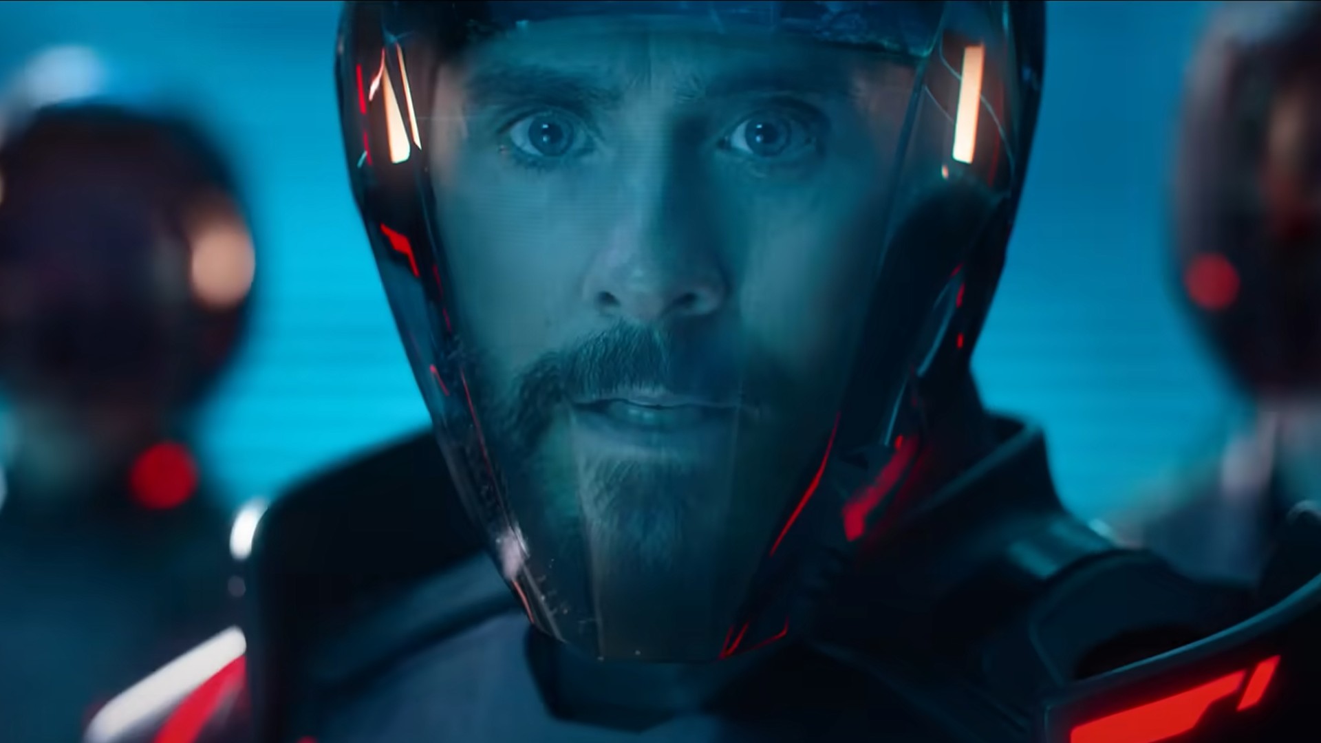 a bearded man in a motorcycle helmet with a clear visor looks concernedly at something behind the viewer