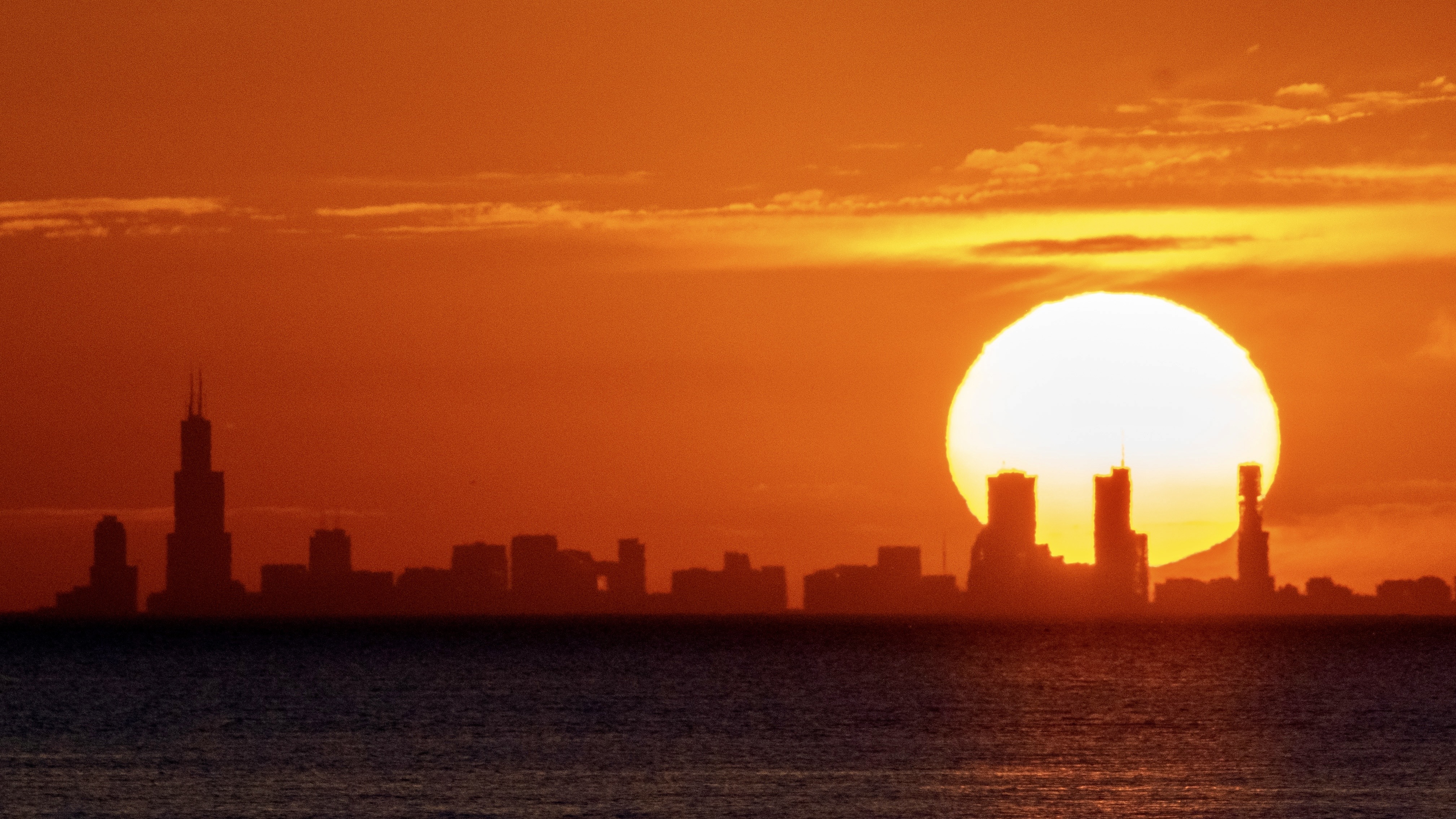 a bright sun in an orange-and-red sky above a city skyline