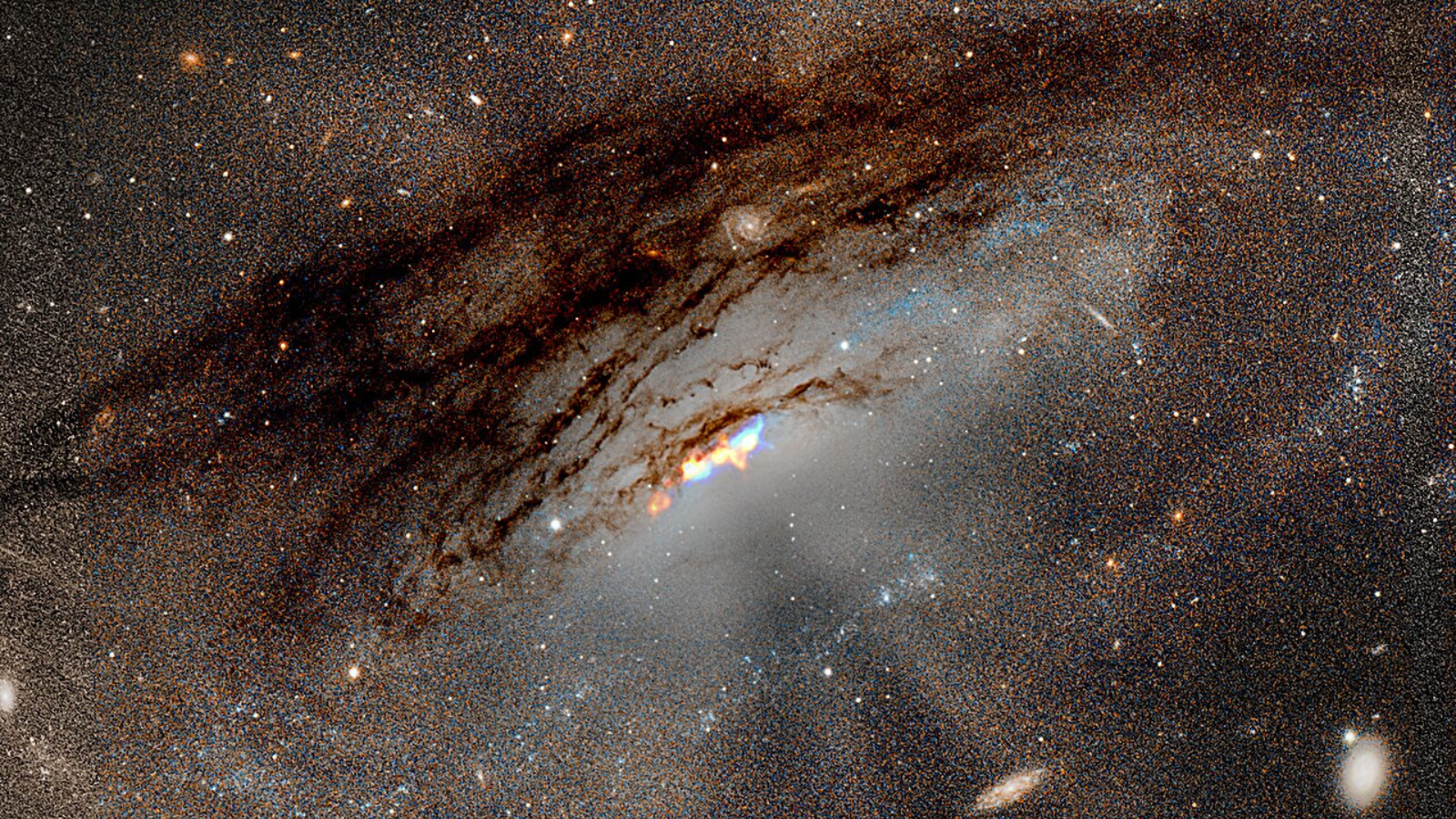 A composite view of the galaxy IC5063 taken with the JWST's MIRI instrument with the background supplied by Hubble